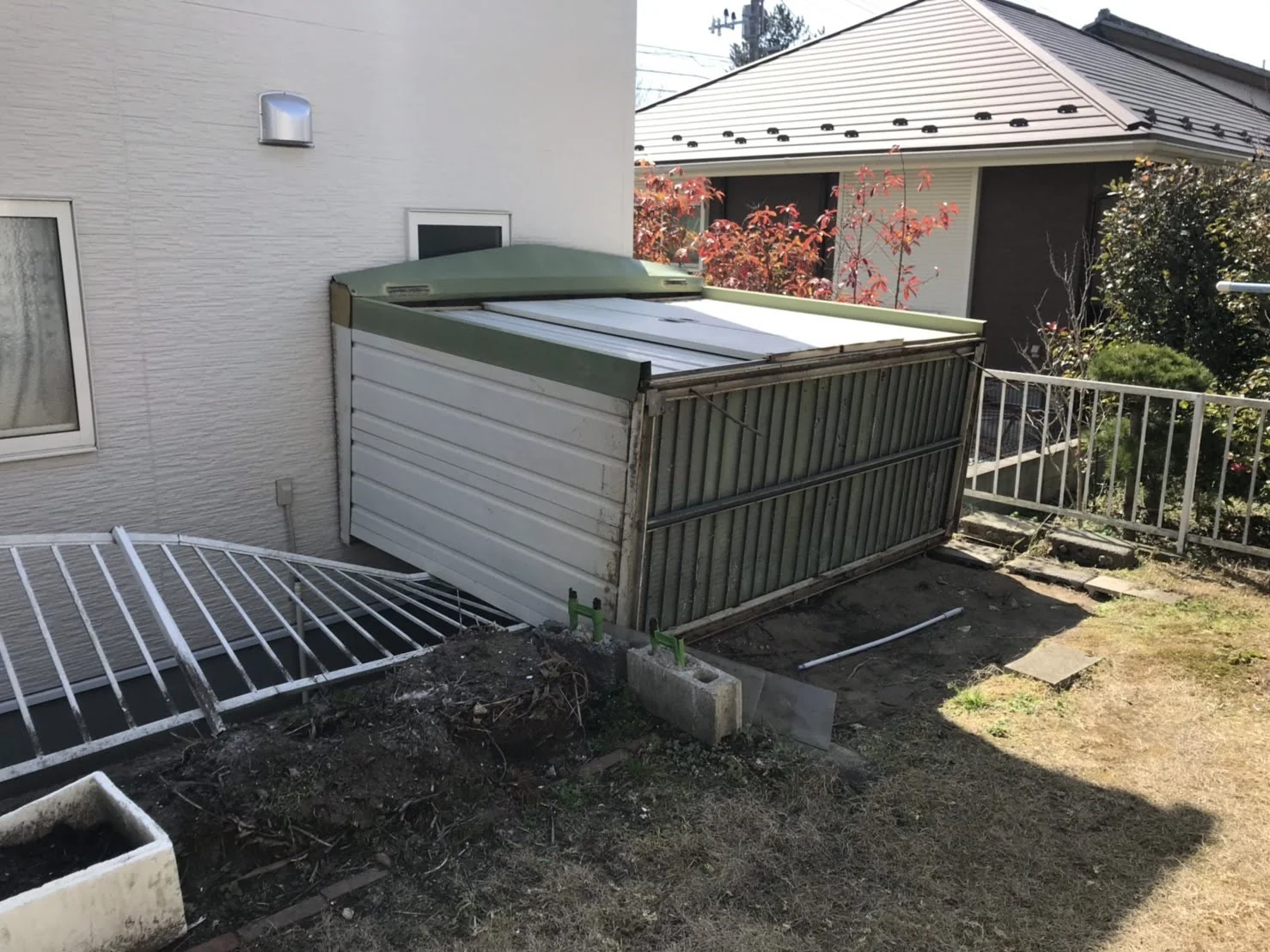 住宅脇に設置された古い緑色の物置側面